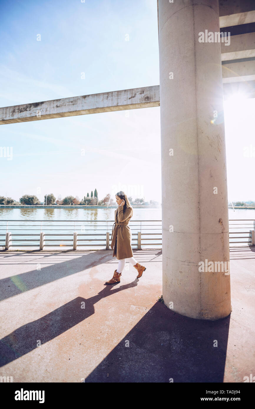 Giovane donna a piedi a un lago in controluce Foto Stock