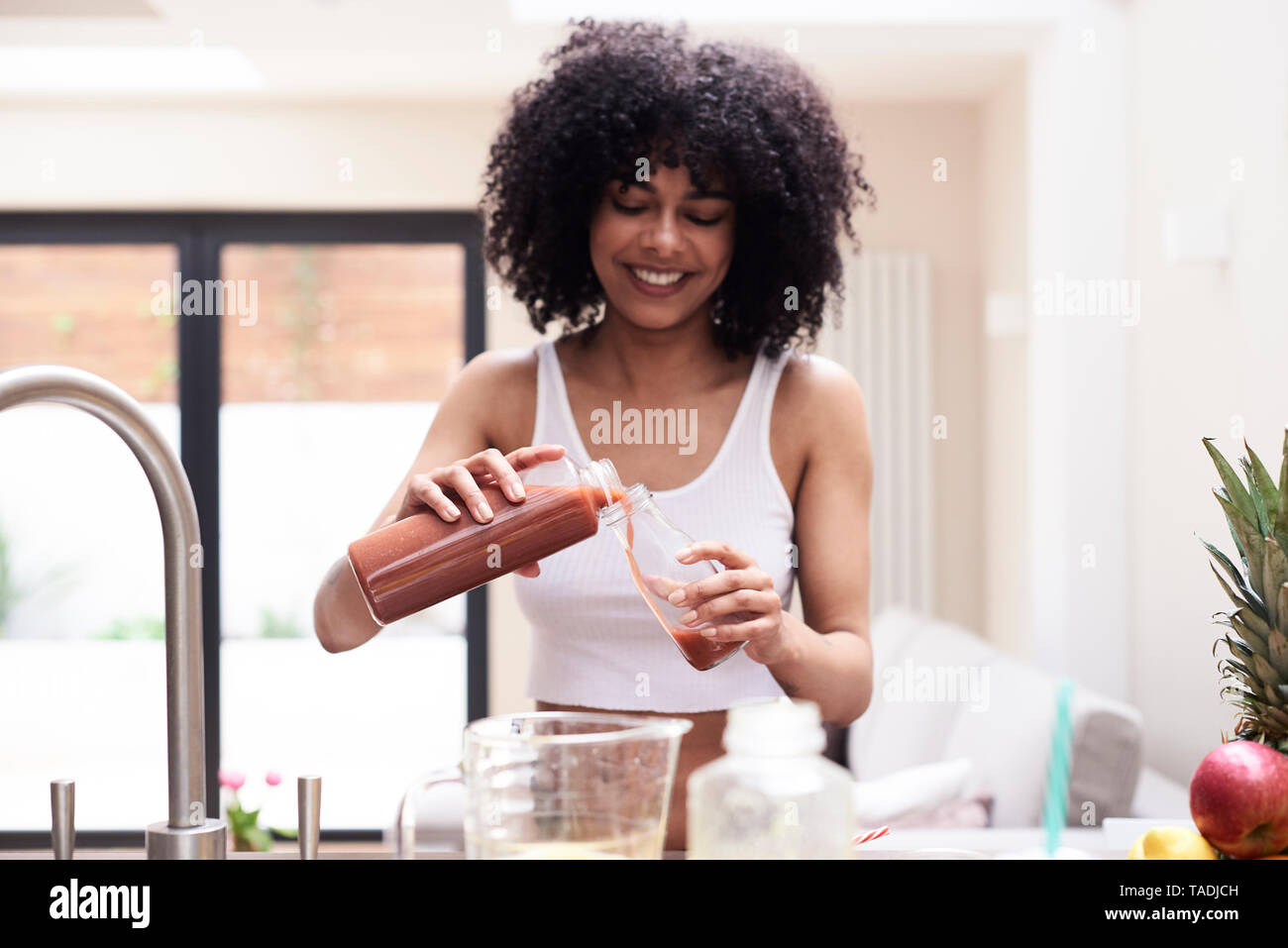Sorridente giovane donna preparazione frullato sano in cucina Foto Stock