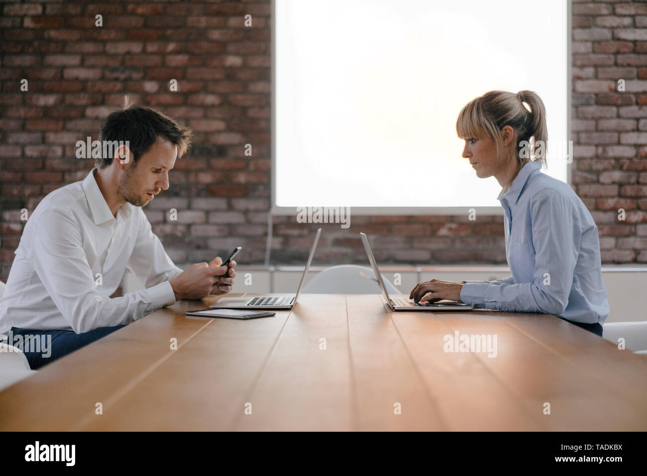 Imprenditore e donna seduta alla scrivania, lavorando sul computer portatile Foto Stock