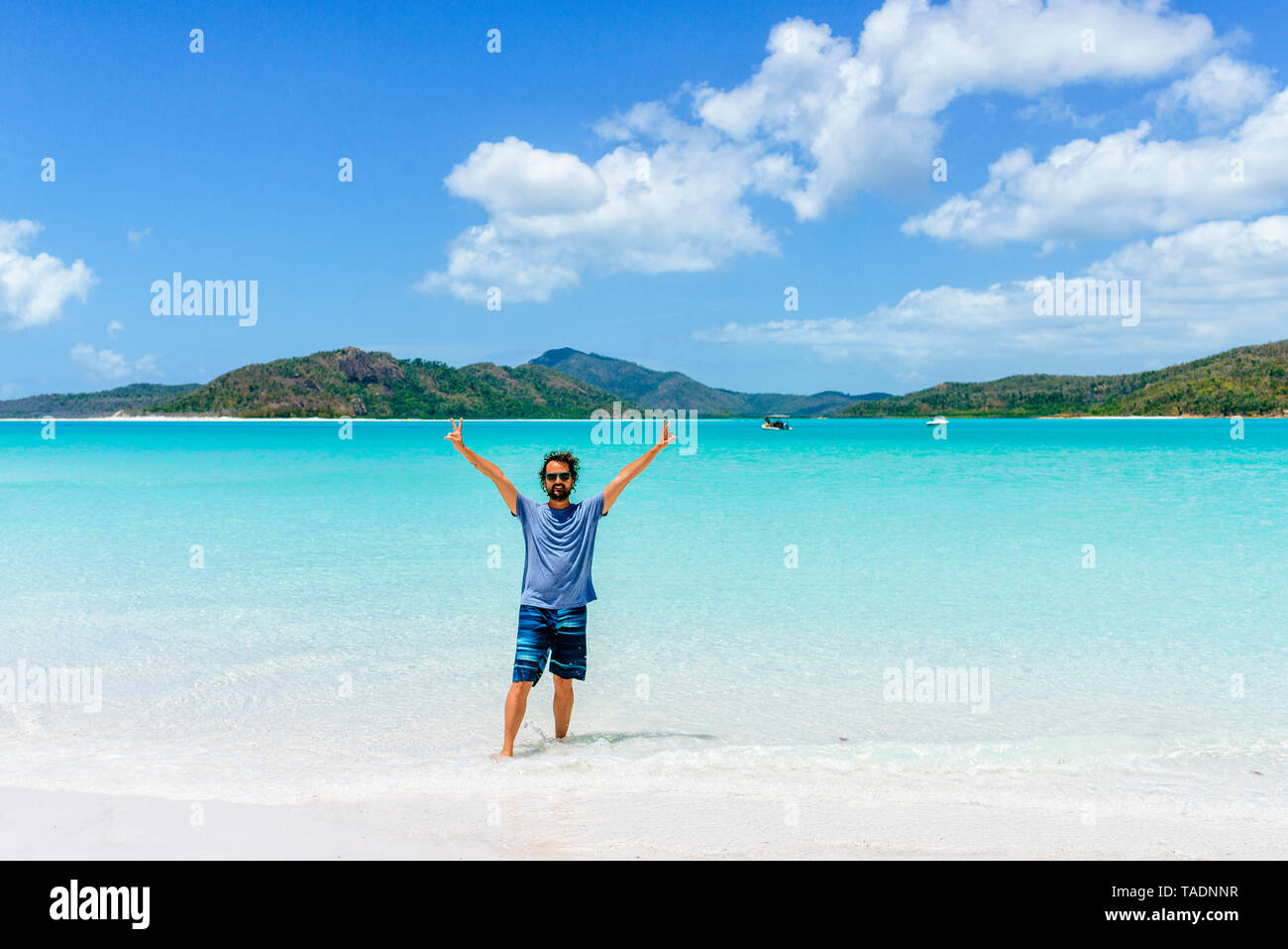 Australia, Queensland, Whitsunday Island, l'uomo con i bracci sollevati in piedi a Whitehaven Beach Foto Stock