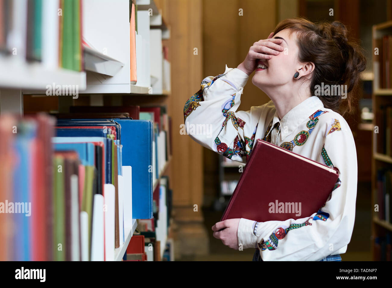 Studentessa libro di lettura in una biblioteca pubblica Foto Stock