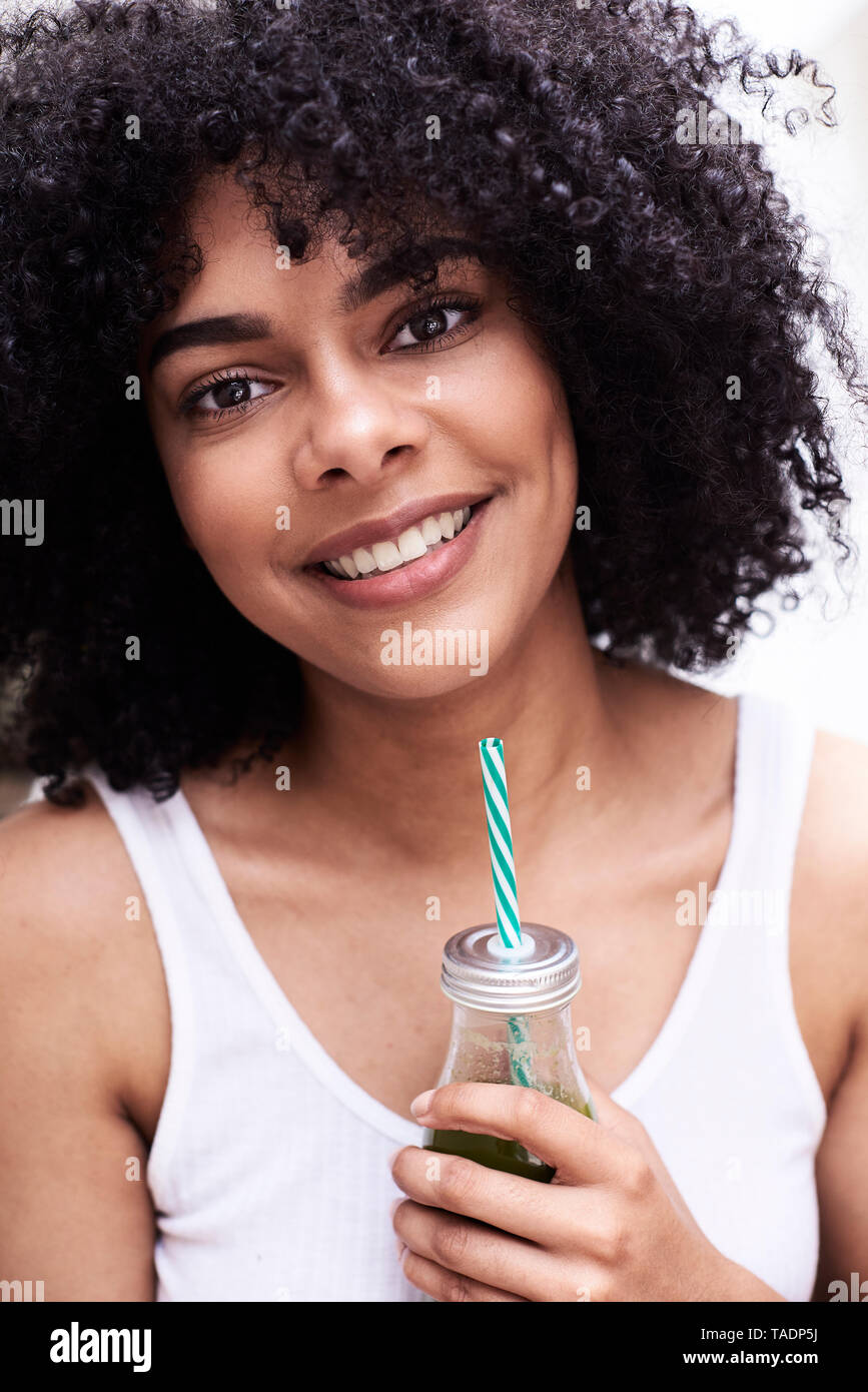 Ritratto di sorridente bella giovane donna azienda green frullato sano Foto Stock