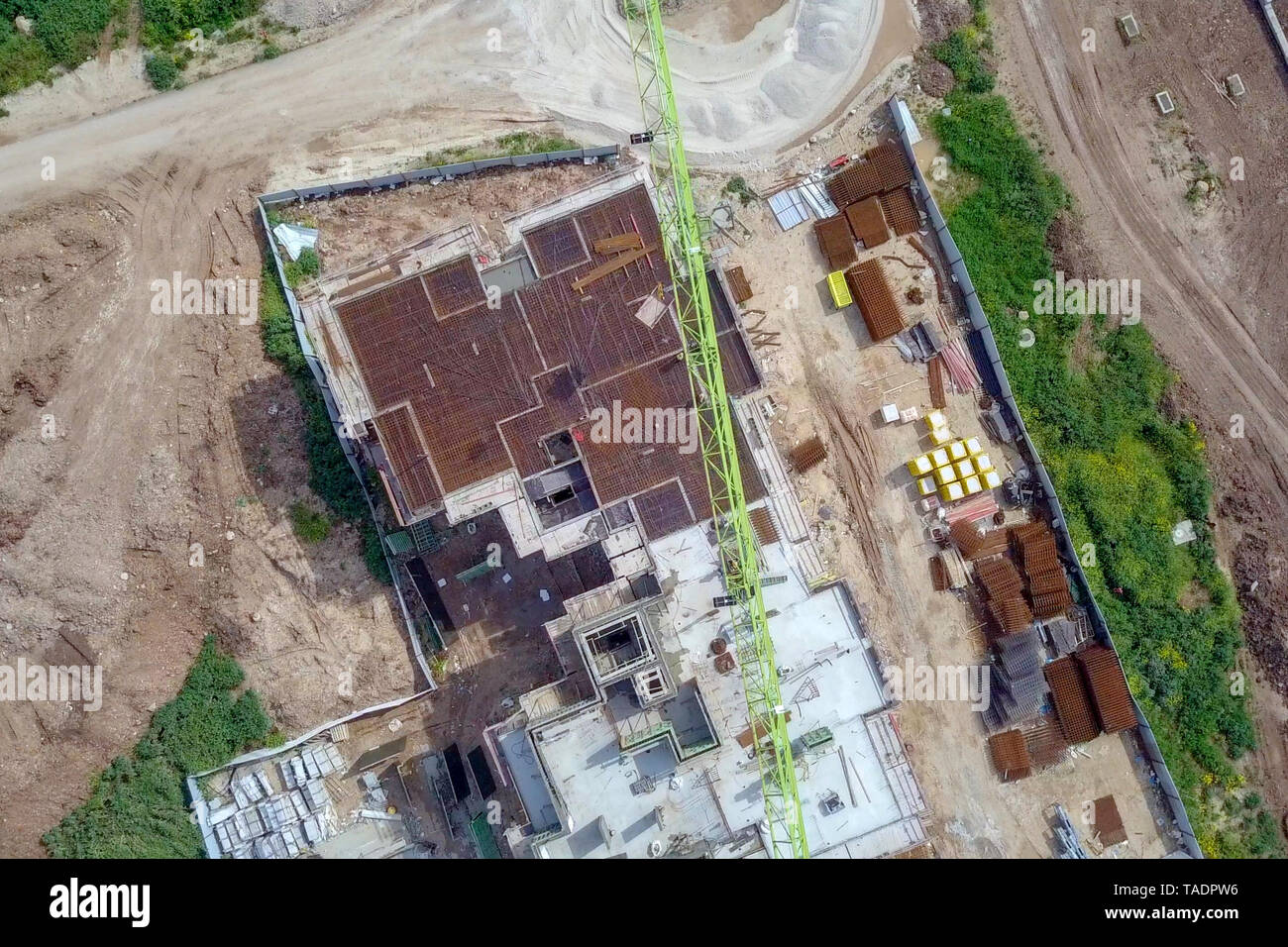 Sito in costruzione - immagine aerea di una grande zona residenziale composto durante le prime fasi di costruzione, con gru e verde ambiente circostante. Foto Stock