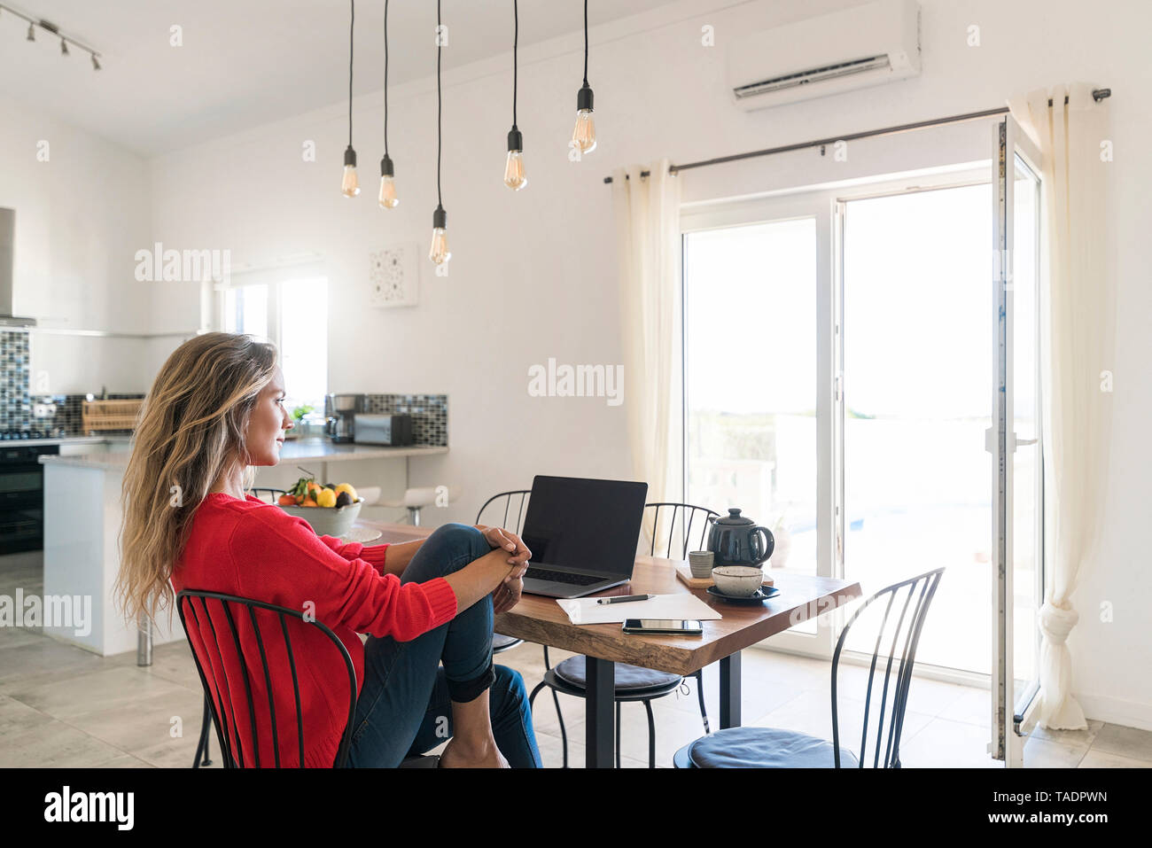 Donna che utilizza sul computer portatile sul tavolo da pranzo in casa moderna Foto Stock