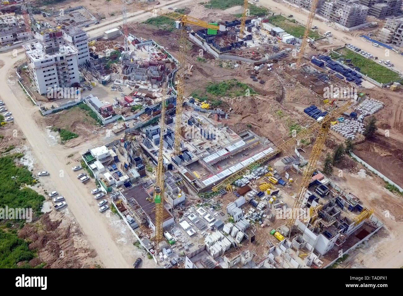 Sito in costruzione - immagine aerea di una grande zona residenziale composto durante le prime fasi di costruzione, con gru e verde ambiente circostante. Foto Stock