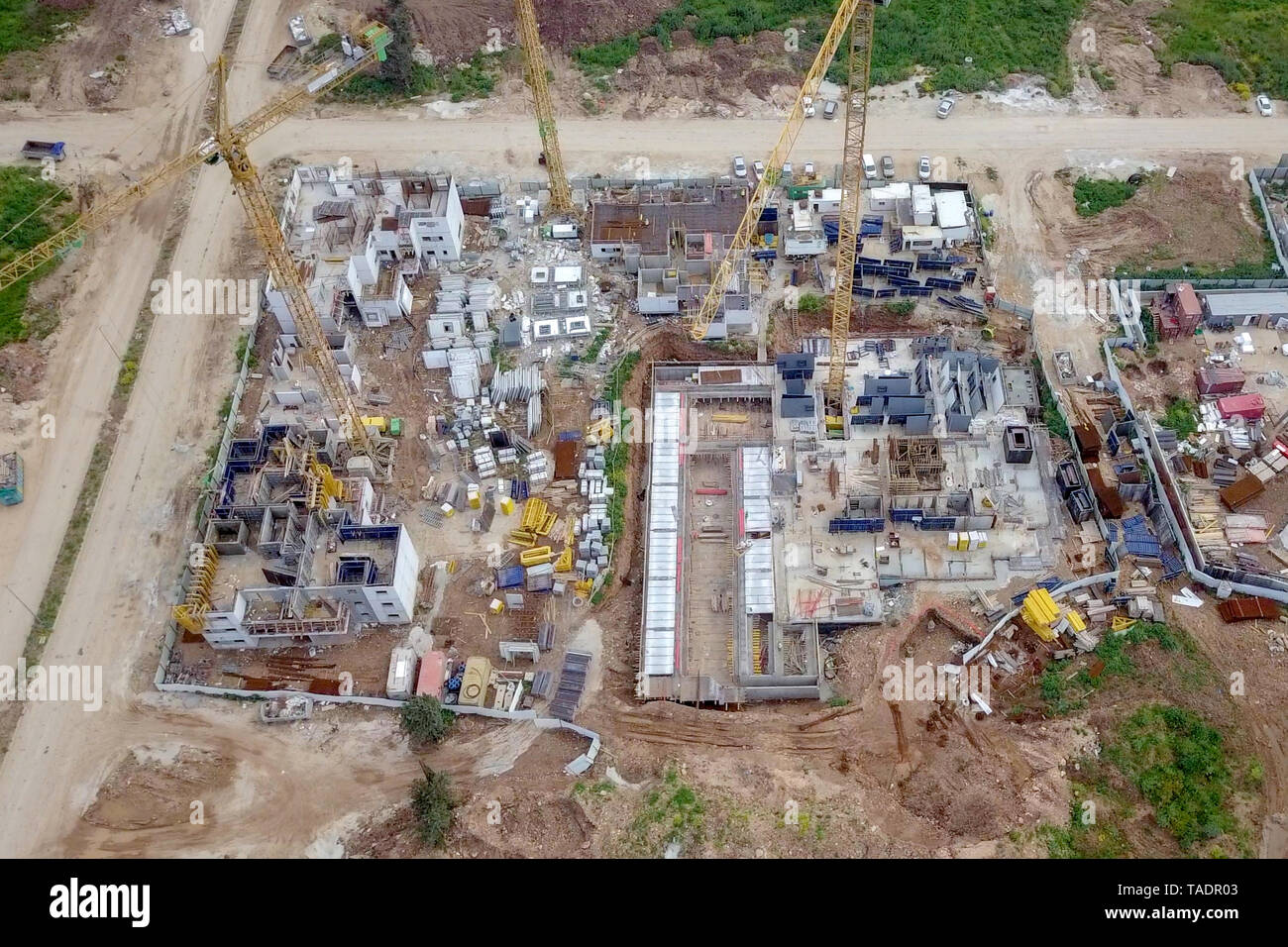 Sito in costruzione - immagine aerea di una grande zona residenziale composto durante le prime fasi di costruzione, con gru e verde ambiente circostante. Foto Stock
