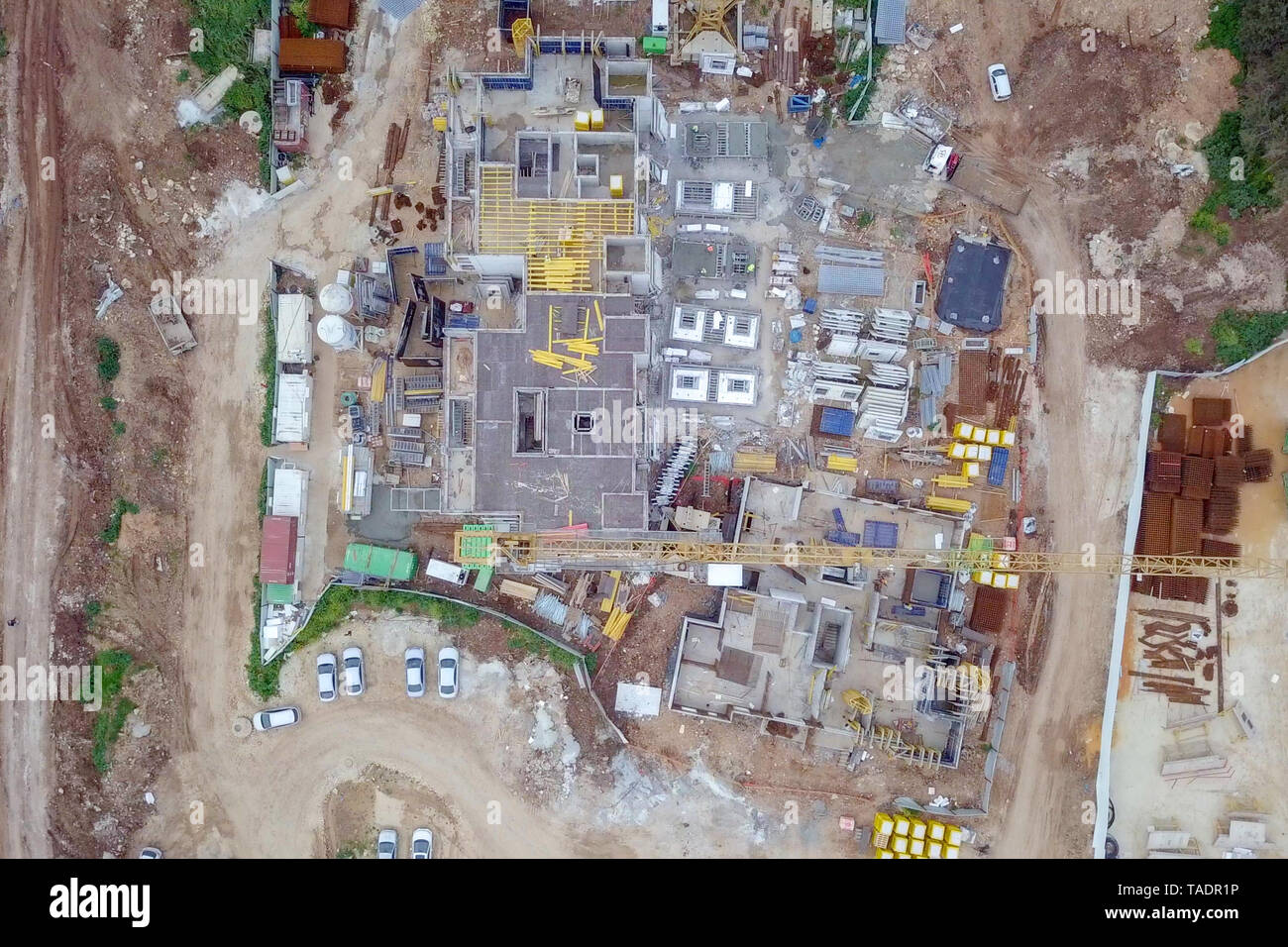 Sito in costruzione - immagine aerea di una grande zona residenziale composto durante le prime fasi di costruzione, con gru e verde ambiente circostante. Foto Stock