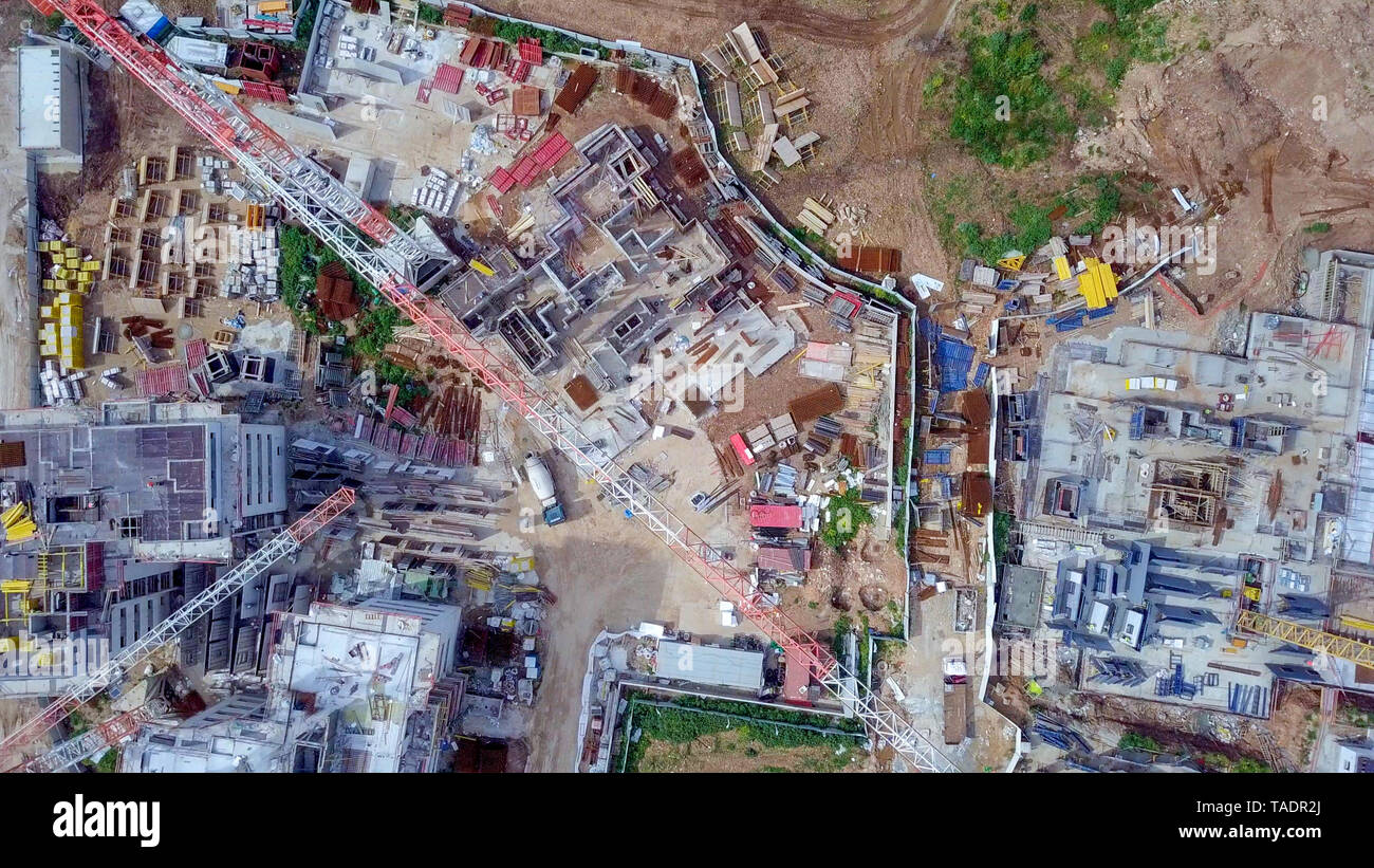 Sito in costruzione - immagine aerea di una grande zona residenziale composto durante le prime fasi di costruzione, con gru e verde ambiente circostante. Foto Stock