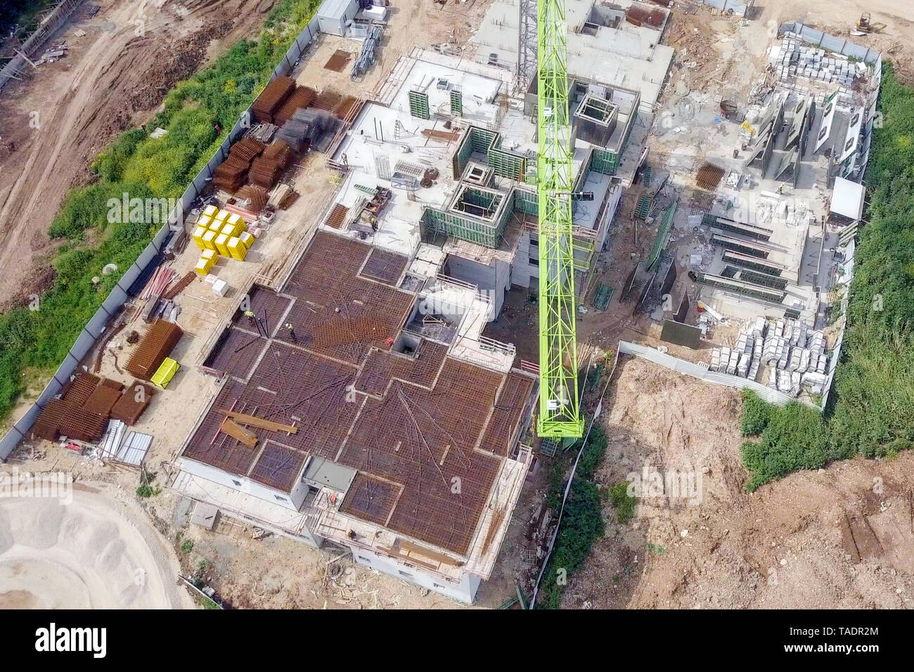 Sito in costruzione - immagine aerea di una grande zona residenziale composto durante le prime fasi di costruzione, con gru e verde ambiente circostante. Foto Stock