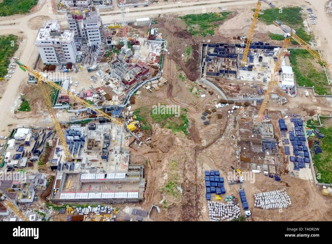 Sito in costruzione - immagine aerea di una grande zona residenziale composto durante le prime fasi di costruzione, con gru e verde ambiente circostante. Foto Stock