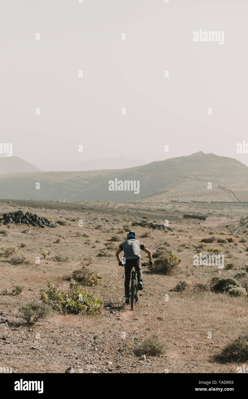 Spagna, Lanzarote, mountainbiker su un viaggio nel paesaggio desertico Foto Stock