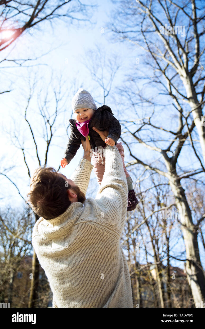 Padre sollevamento felice figlia in posizione di parcheggio Foto Stock