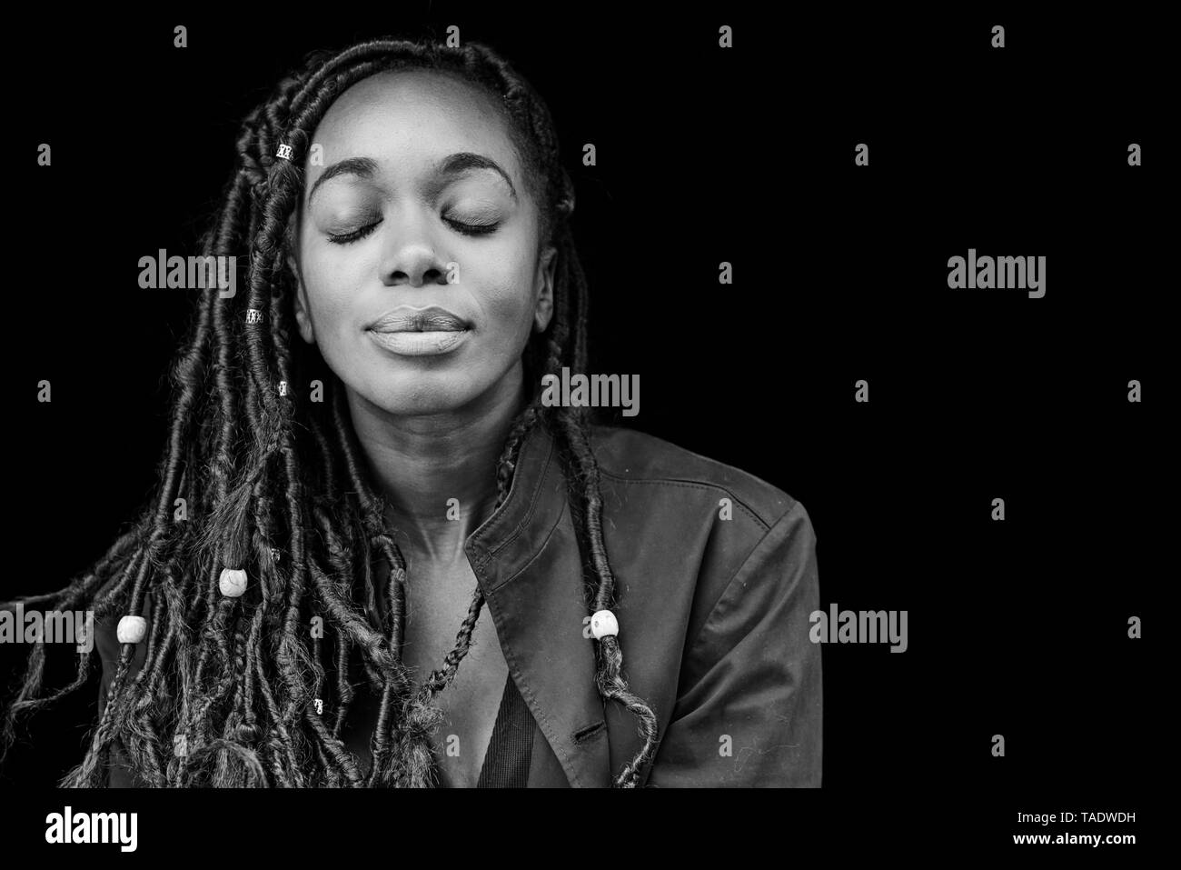 Ritratto di donna con dreadlocks davanti a sfondo nero Foto Stock