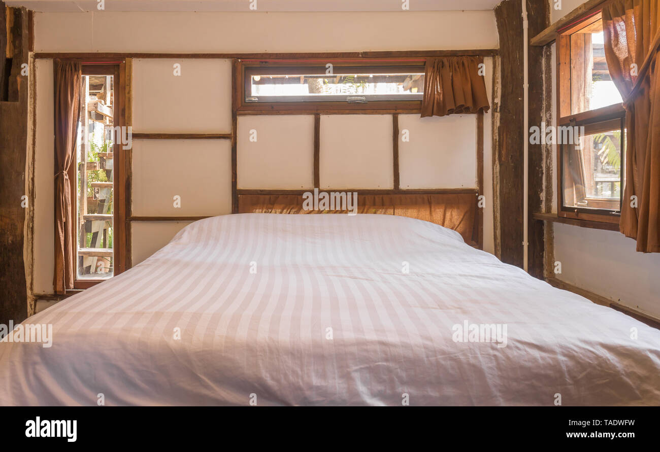 Letto bianco in camera da letto in soppalco Paese Interior Design Camera Vista anteriore. Interior design camera includono una lampada e aria condizionata e le finestre. Interior design Foto Stock
