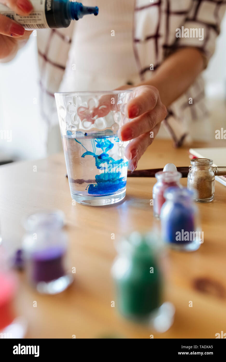 Pittore liquido di riempimento colore in un bicchiere di acqua, vista parziale Foto Stock