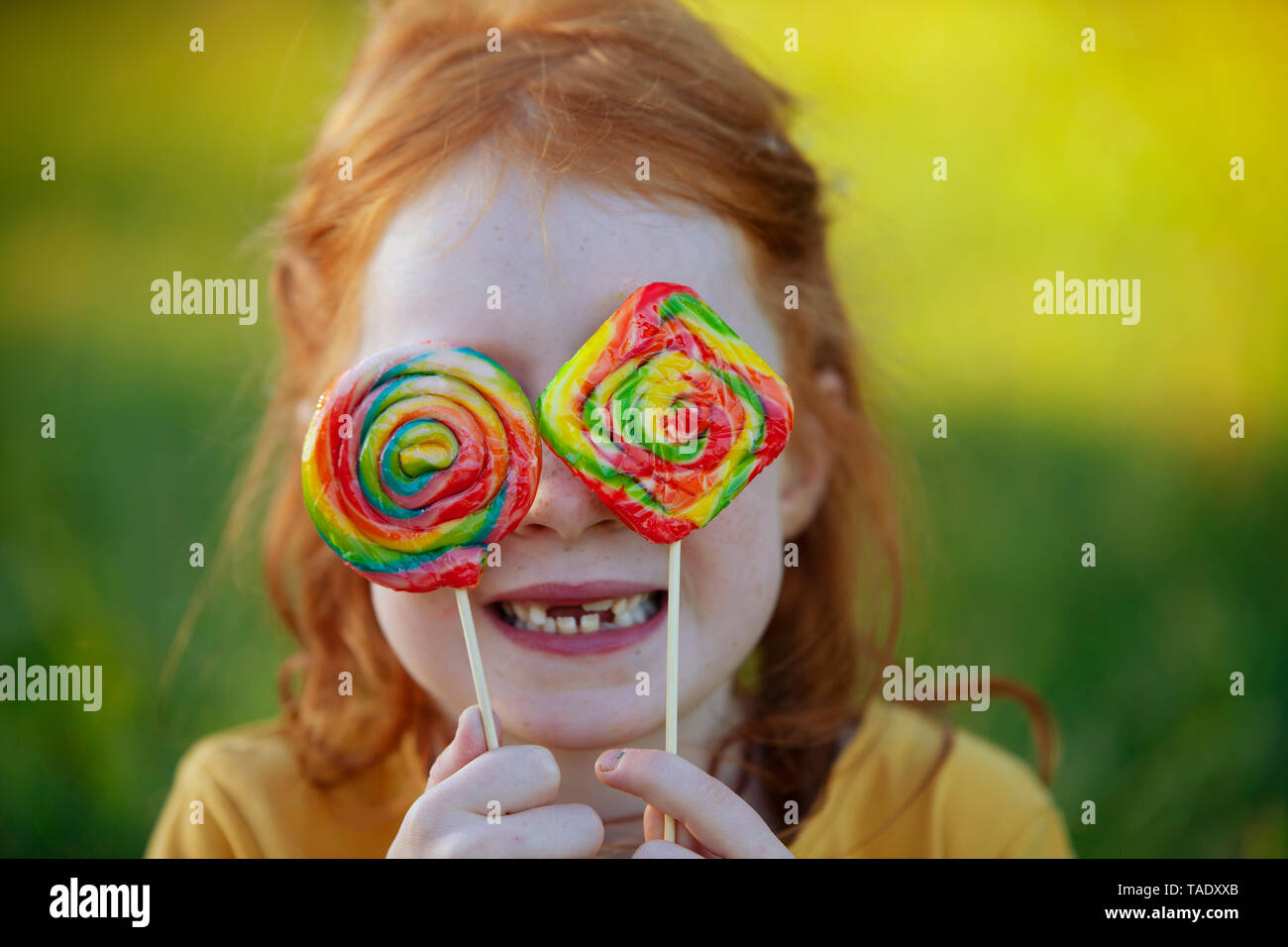Felice ragazza che copre la sua gli occhi con connettori lollipop Foto Stock