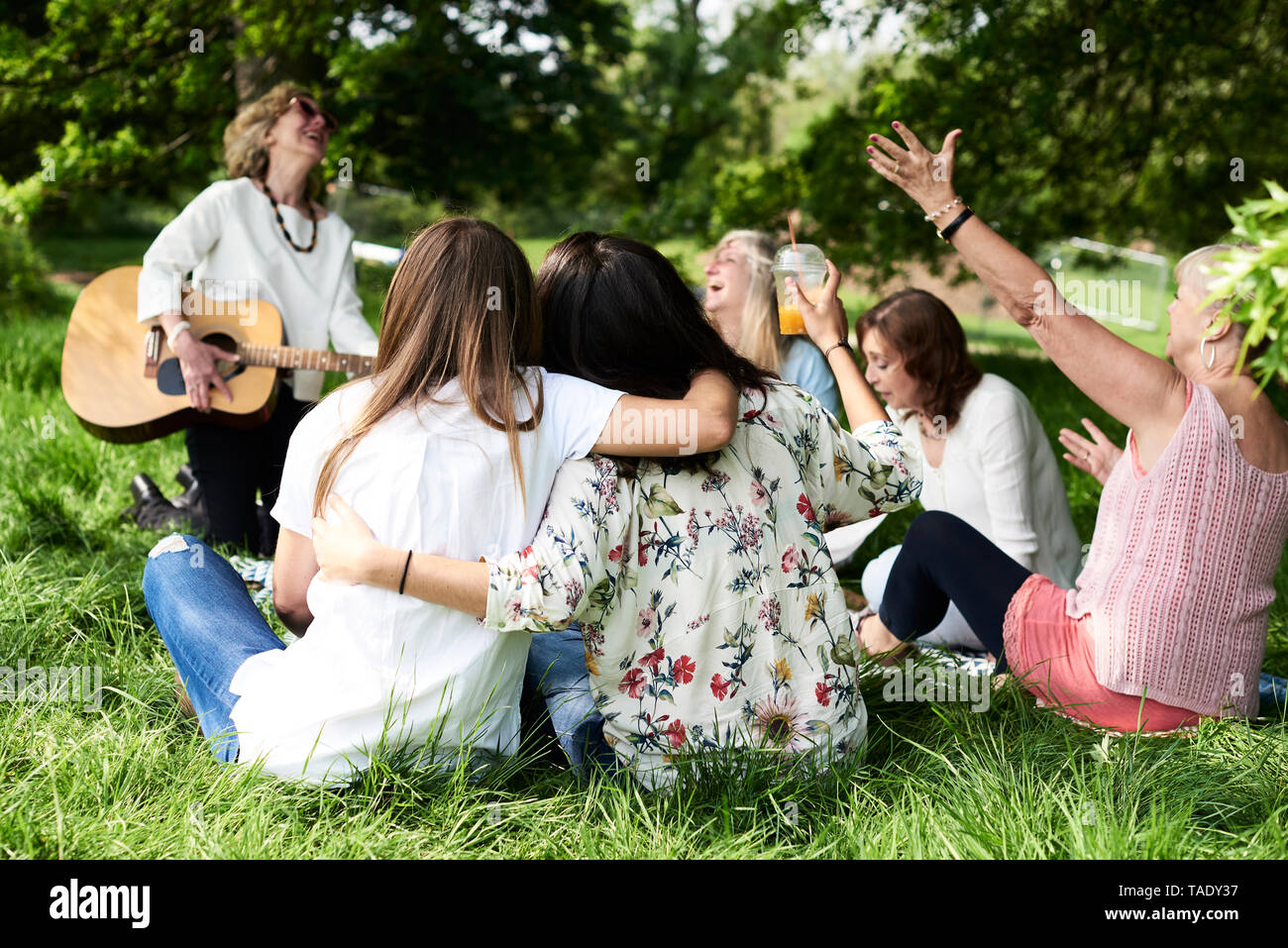 Il gruppo di donne con guitar avente il divertimento a un picnic nel parco Foto Stock