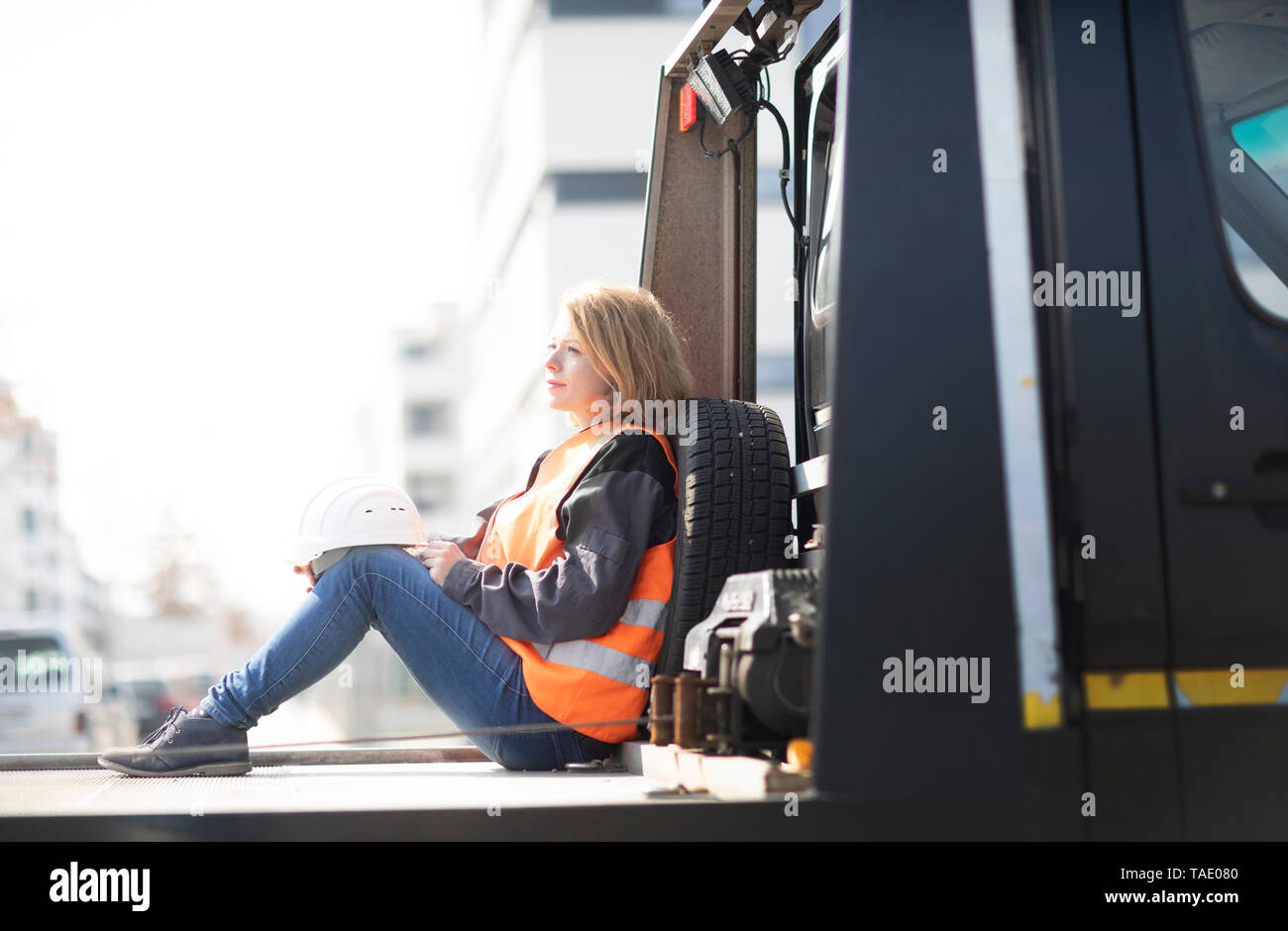 Donna che indossa giubbotto seduto sulla piattaforma del carrello Foto Stock