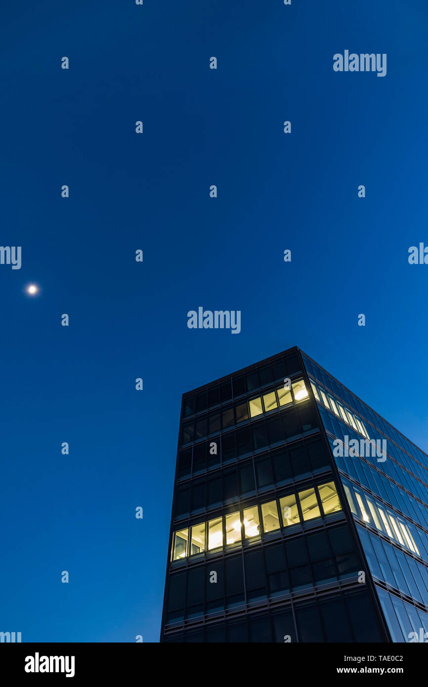 Germania, Stoccarda, finestre illuminate a ufficio moderno edificio a ora di blu Foto Stock
