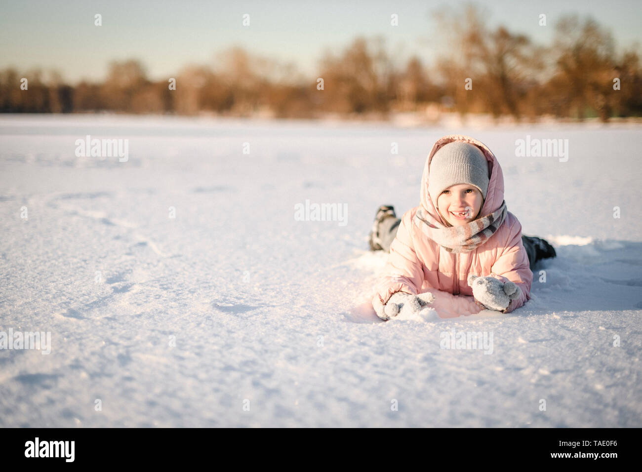 Ritratto di bambina giacente nel campo di neve Foto Stock