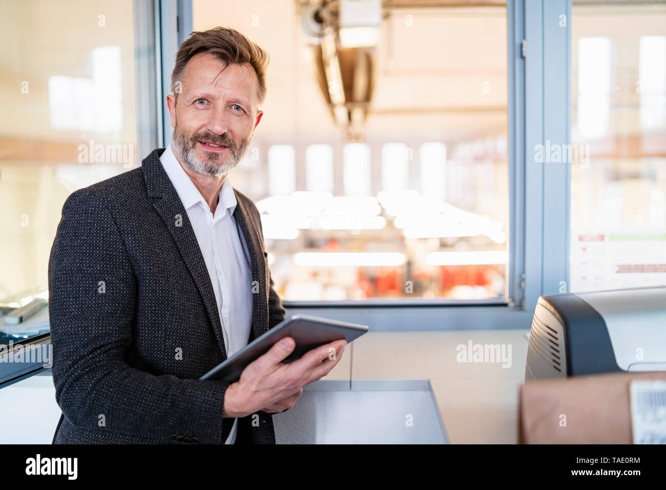 Ritratto di imprenditore utilizzando tablet presso la finestra con lo sfondo di fabbrica Foto Stock