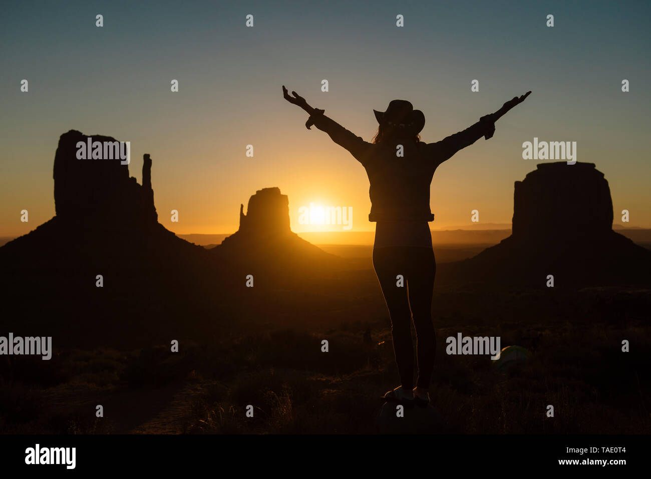 Stati Uniti d'America, Utah, Monument Valley, silhouette di donna felice con il cappello da cowboy godendo di sunrise Foto Stock