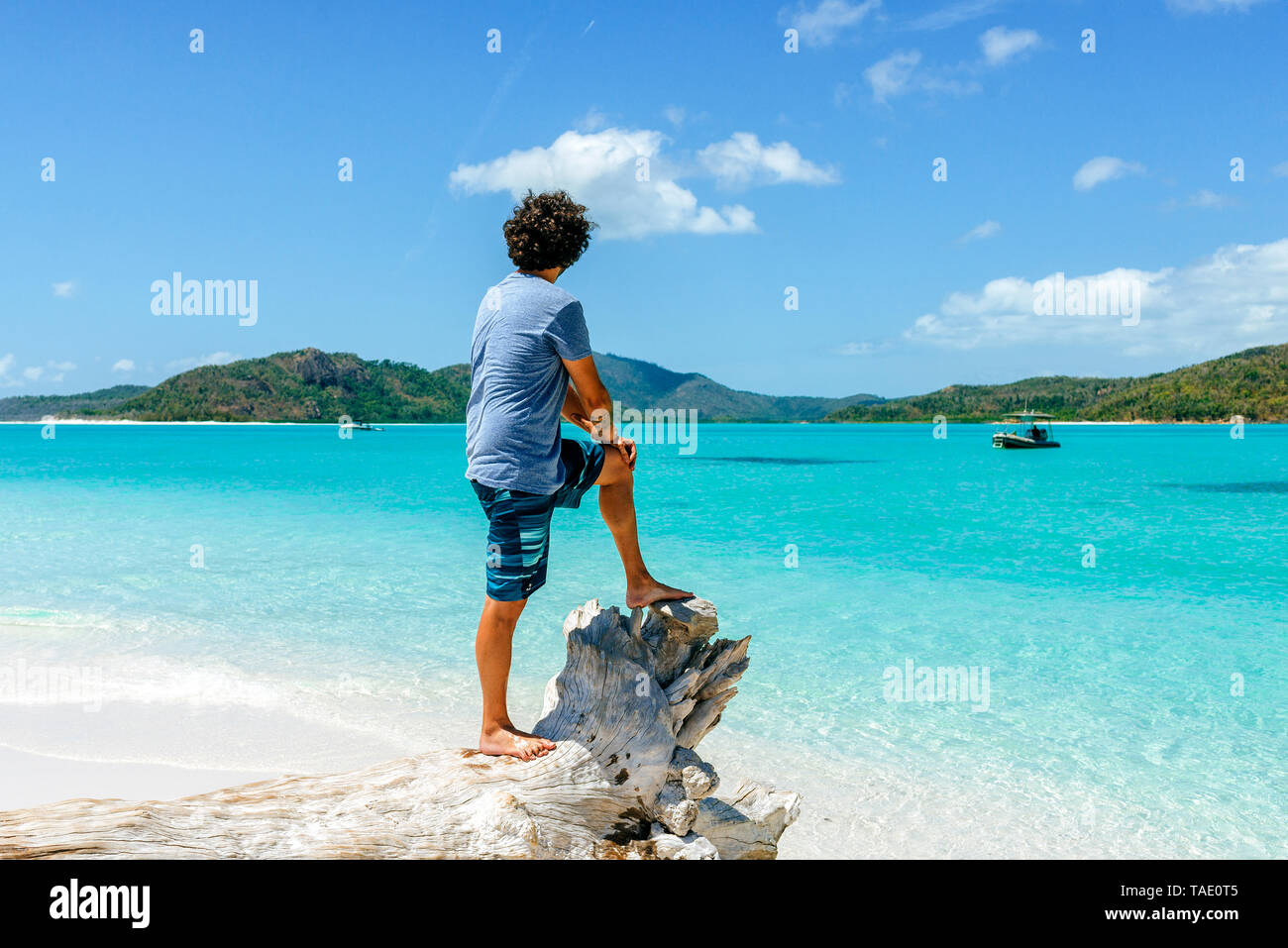 Australia, Queensland, Whitsunday Island, uomo in piedi sul log in corrispondenza di Whitehaven Beach Foto Stock