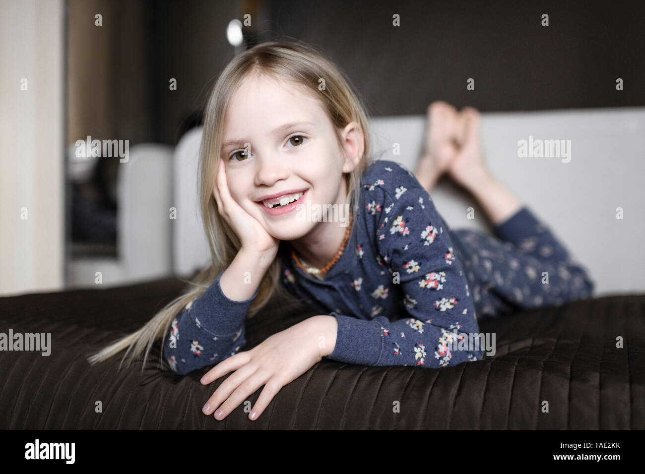 Ritratto di sorridente bambina con dente divario rilassante sul lettino a casa Foto Stock
