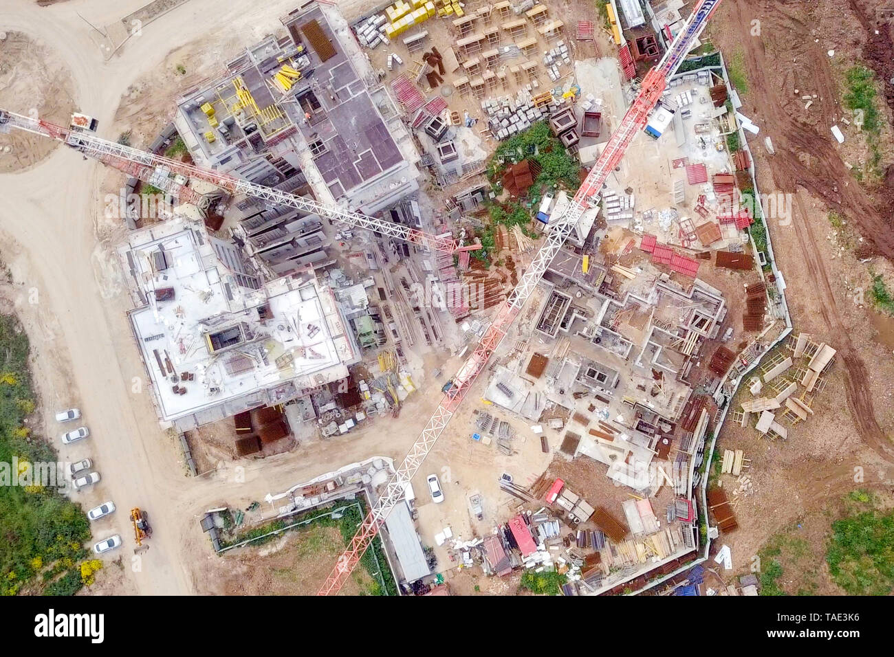 Sito in costruzione - immagine aerea di una grande zona residenziale composto durante le prime fasi di costruzione, con gru e verde ambiente circostante. Foto Stock