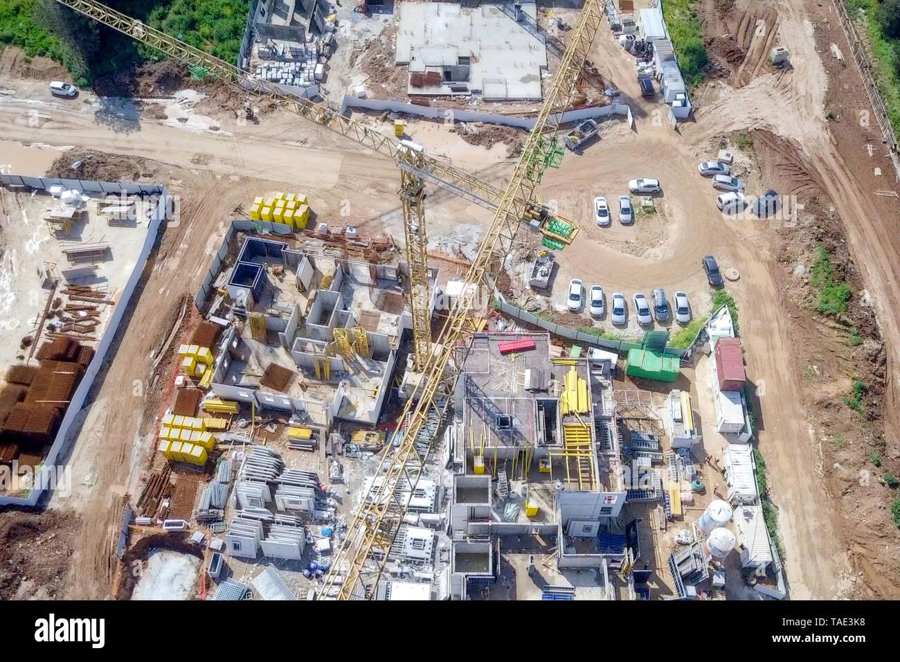 Sito in costruzione - immagine aerea di una grande zona residenziale composto durante le prime fasi di costruzione, con gru e verde ambiente circostante. Foto Stock