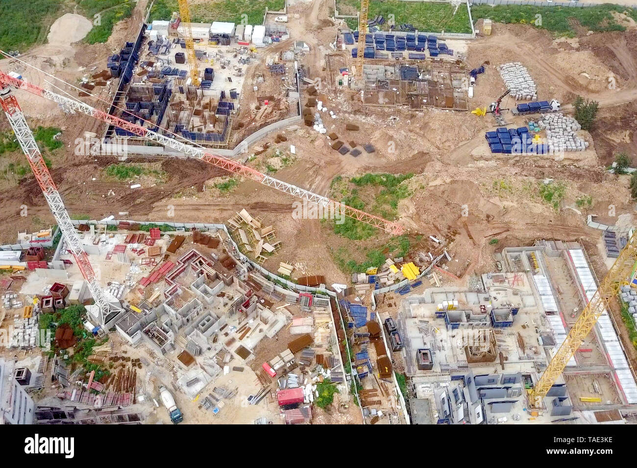 Sito in costruzione - immagine aerea di una grande zona residenziale composto durante le prime fasi di costruzione, con gru e verde ambiente circostante. Foto Stock