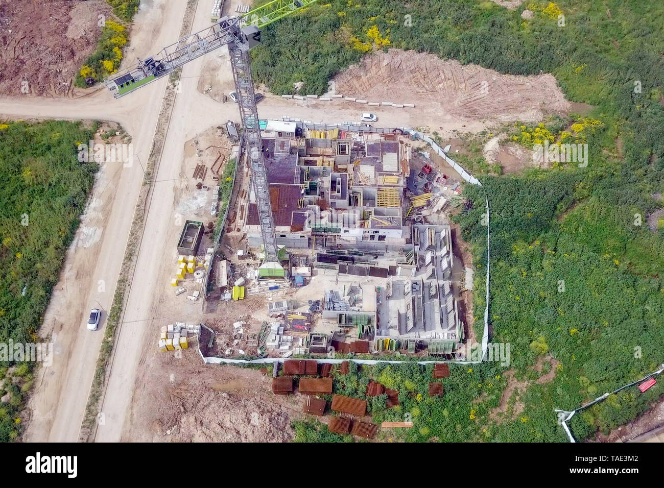 Sito in costruzione - immagine aerea di una grande zona residenziale composto durante le prime fasi di costruzione, con gru e verde ambiente circostante. Foto Stock