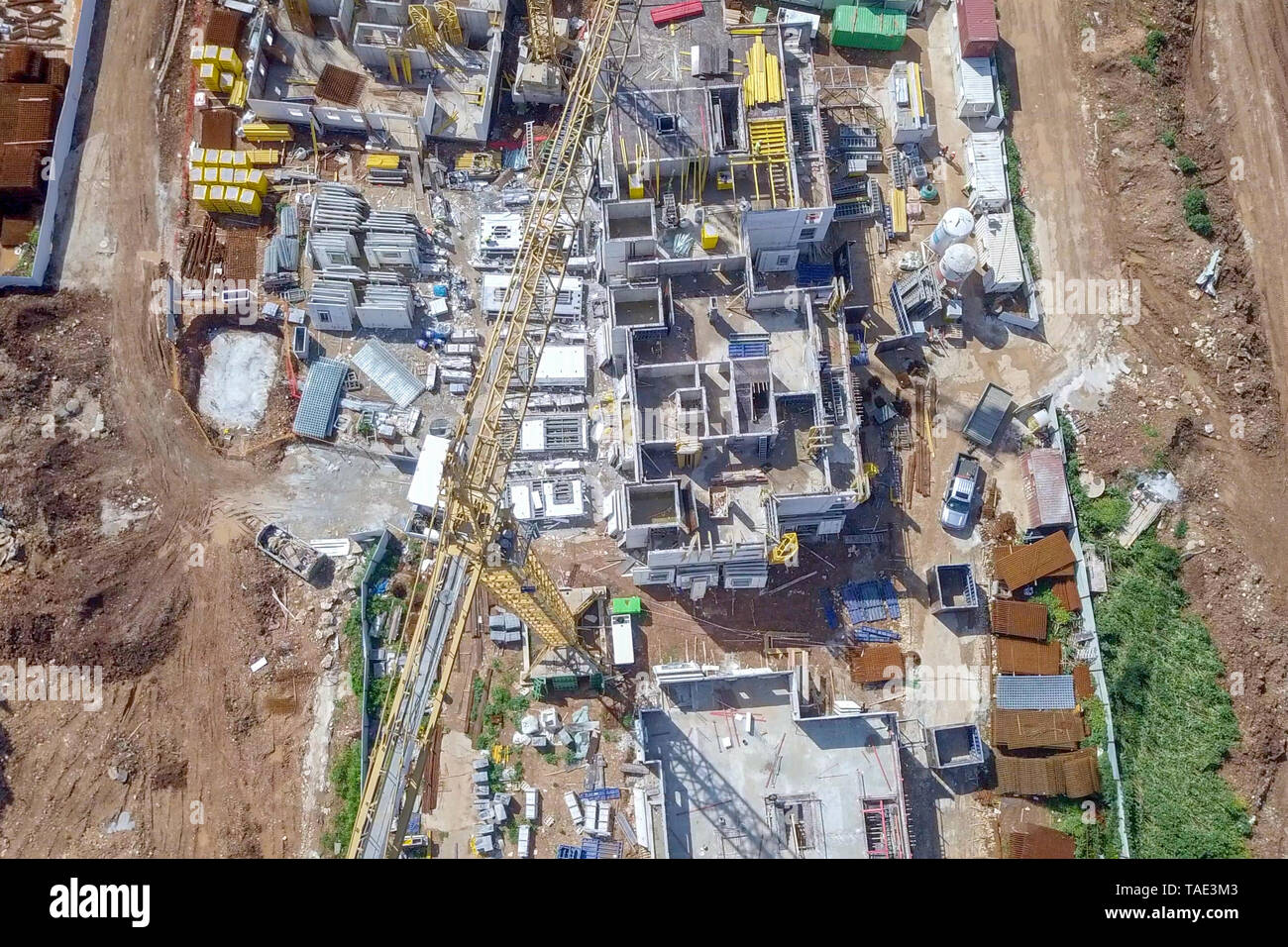 Sito in costruzione - immagine aerea di una grande zona residenziale composto durante le prime fasi di costruzione, con gru e verde ambiente circostante. Foto Stock