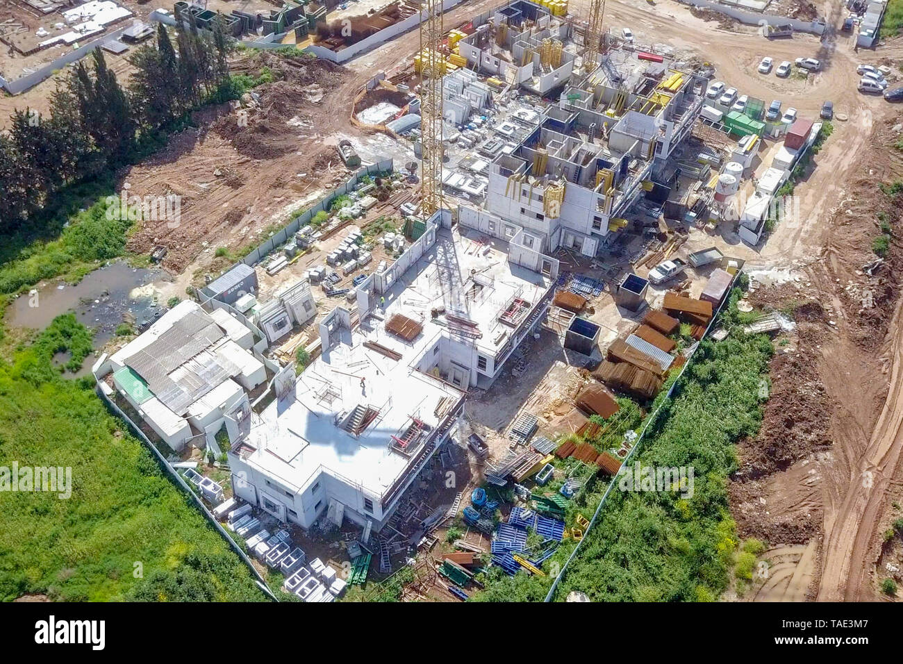 Sito in costruzione - immagine aerea di una grande zona residenziale composto durante le prime fasi di costruzione, con gru e verde ambiente circostante. Foto Stock