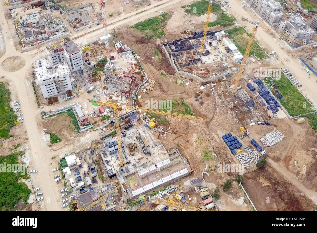 Sito in costruzione - immagine aerea di una grande zona residenziale composto durante le prime fasi di costruzione, con gru e verde ambiente circostante. Foto Stock