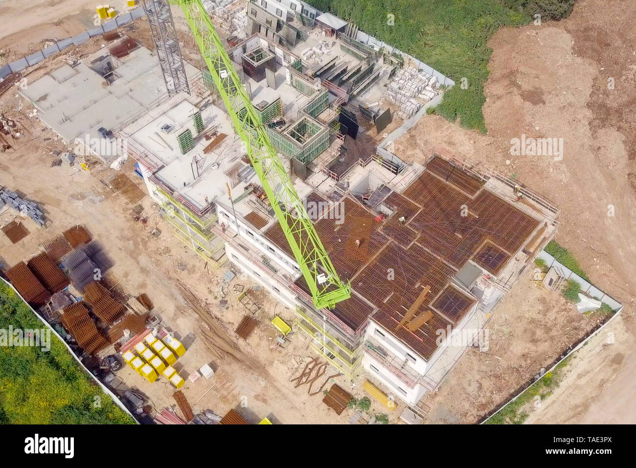 Sito in costruzione - immagine aerea di una grande zona residenziale composto durante le prime fasi di costruzione, con gru e verde ambiente circostante. Foto Stock