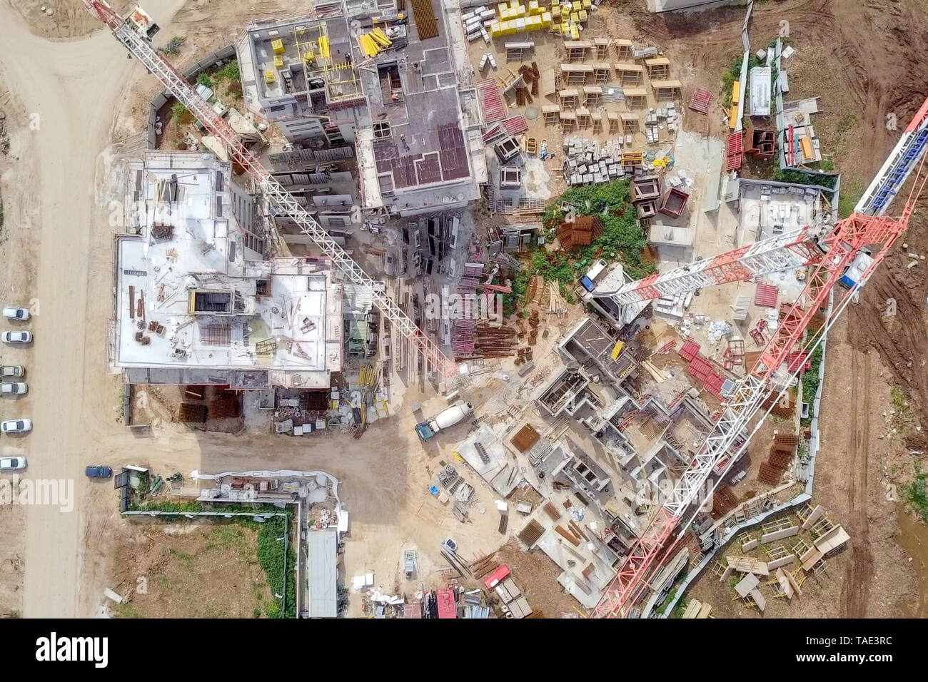 Sito in costruzione - immagine aerea di una grande zona residenziale composto durante le prime fasi di costruzione, con gru e verde ambiente circostante. Foto Stock