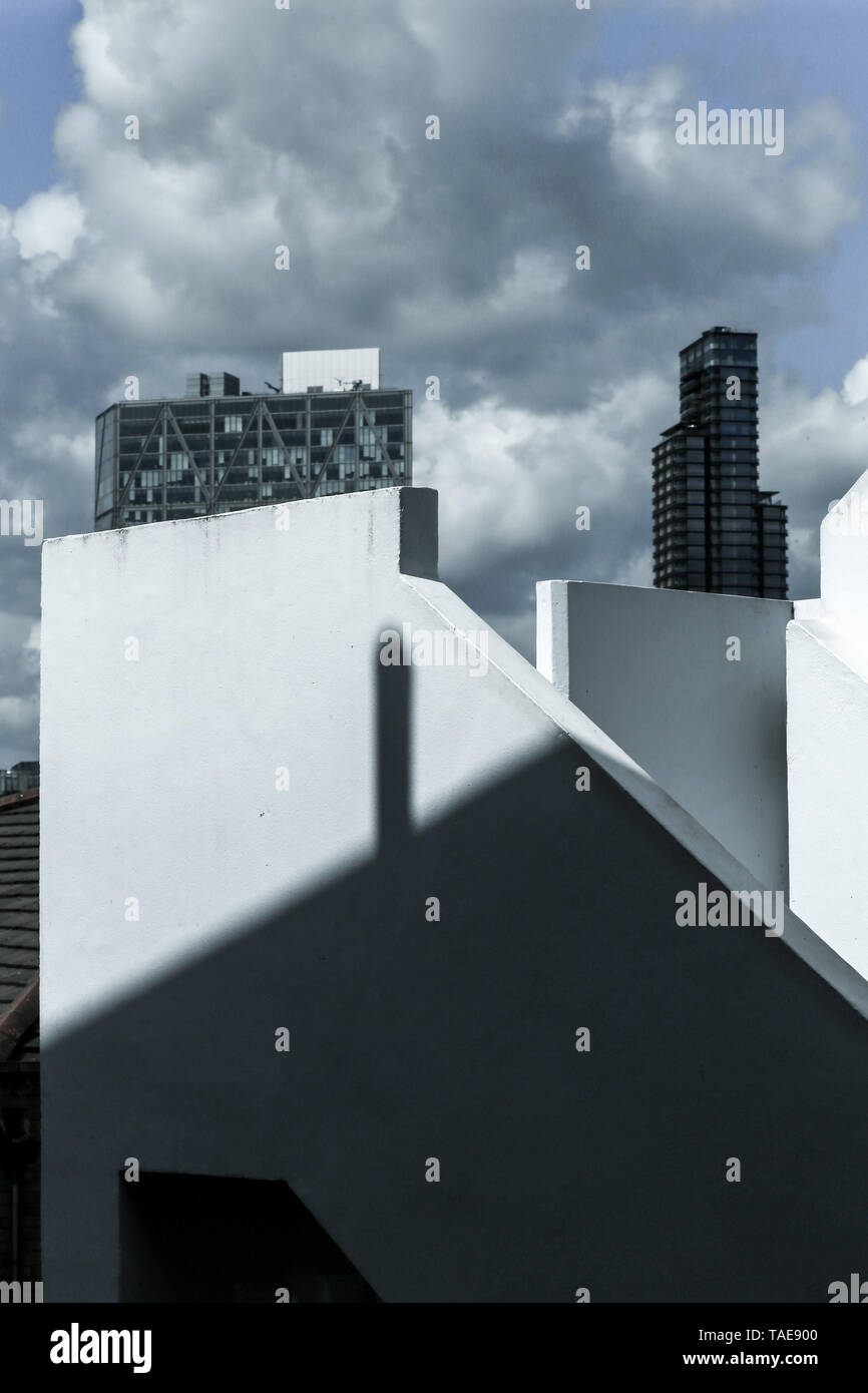 La miscelazione di forme e sagome, stratificazione in architettura moderna - parte di scale e la facciata edificio, inusuale esterno geometrico di giochi di luce. Foto Stock