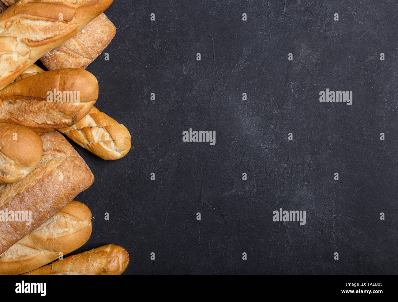 Vari crostini di pane sulla tavola nera. Bordo sinistro, vista dall'alto con lo spazio per il tuo testo. Concetto di banner con pane Foto Stock