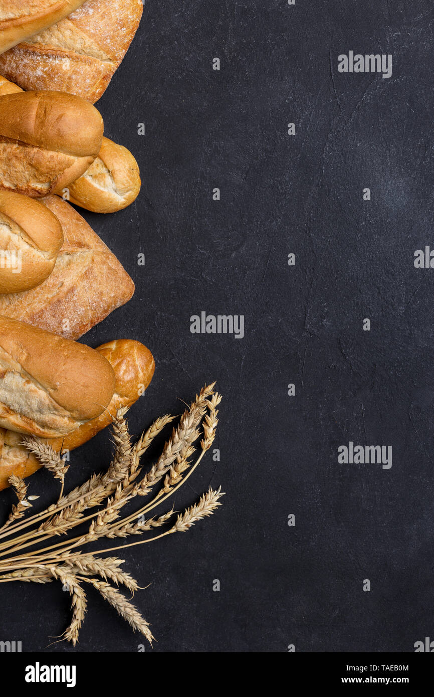 La gamma di tipi di pane fresco con grano. Su sfondo scuro. Spazio libero, vista dall'alto, laici piatta Foto Stock