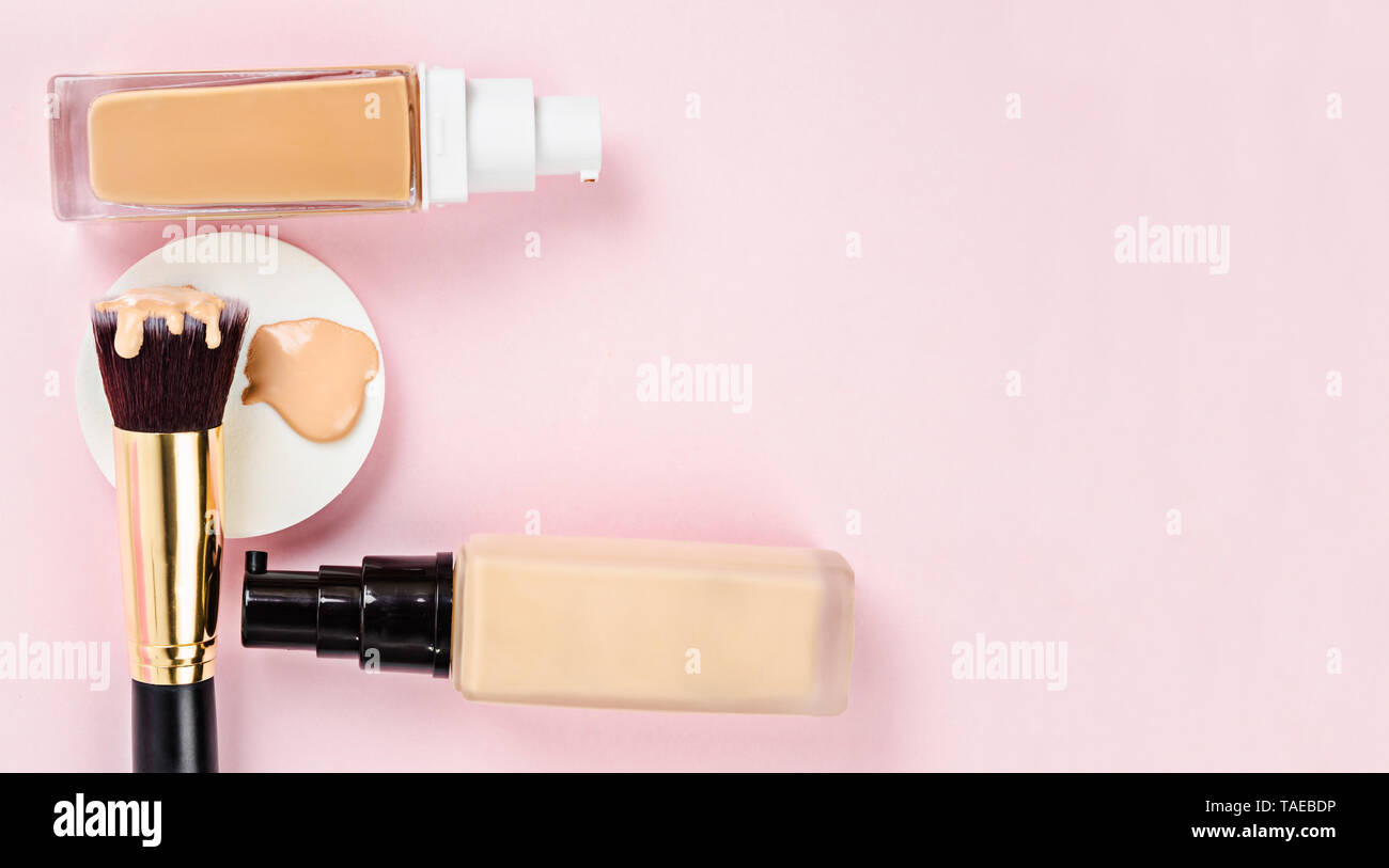 Fluido liquido foundation bottiglia di vetro su spugne per il trucco e trucco pennello su sfondo rosa con spazio libero per il tuo testo o messaggio. Foto Stock