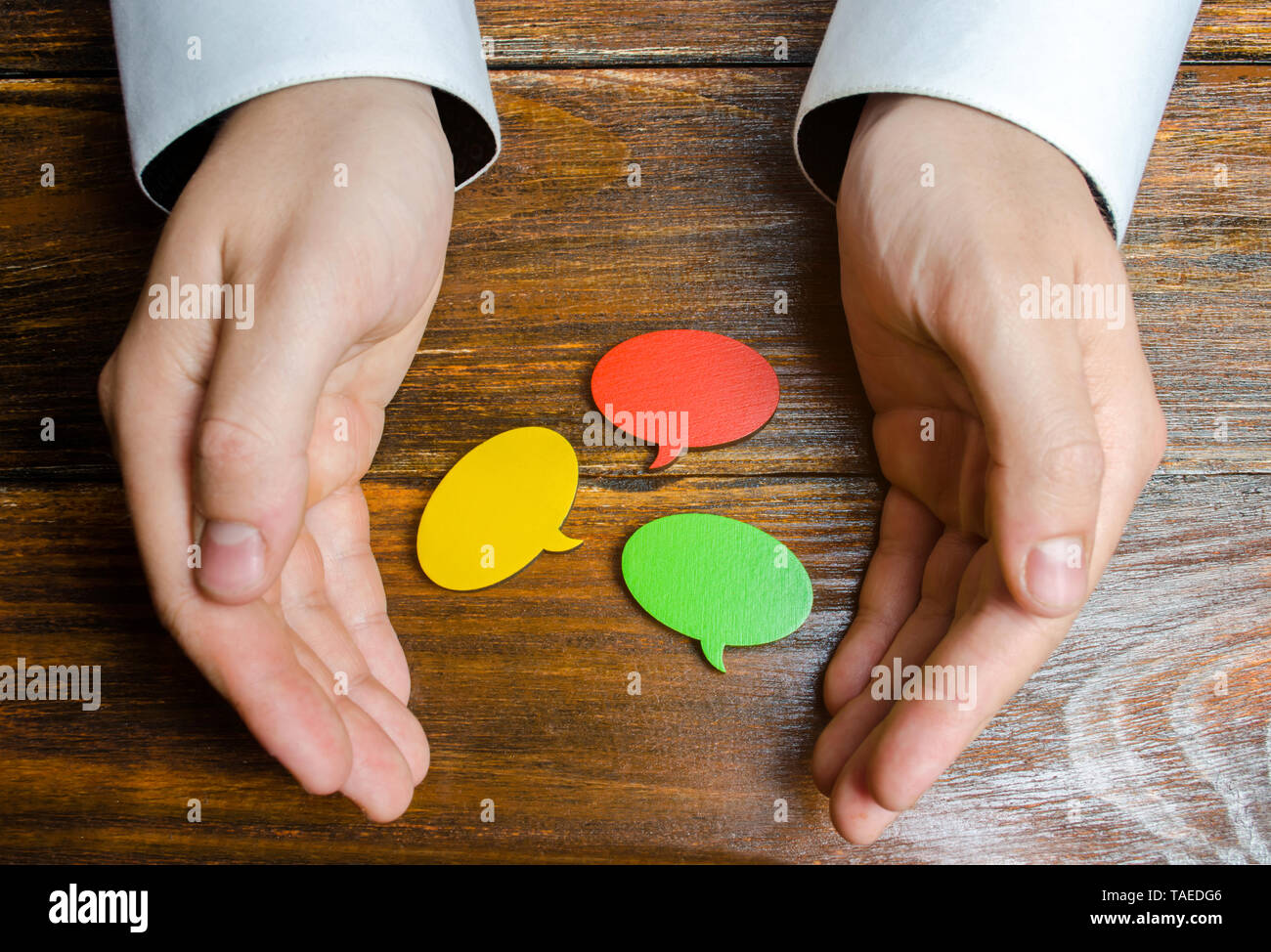 Un uomo raccoglie multicolore di fumetti nelle sue mani. Ascoltare altri pareri e punti di vista, accettando critiche e commenti. Contatti di retromarcia Foto Stock