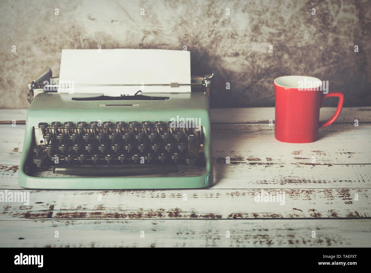 Vecchia macchina da scrivere accanto a una tazza di caffè contro sfondo Grunge Foto Stock