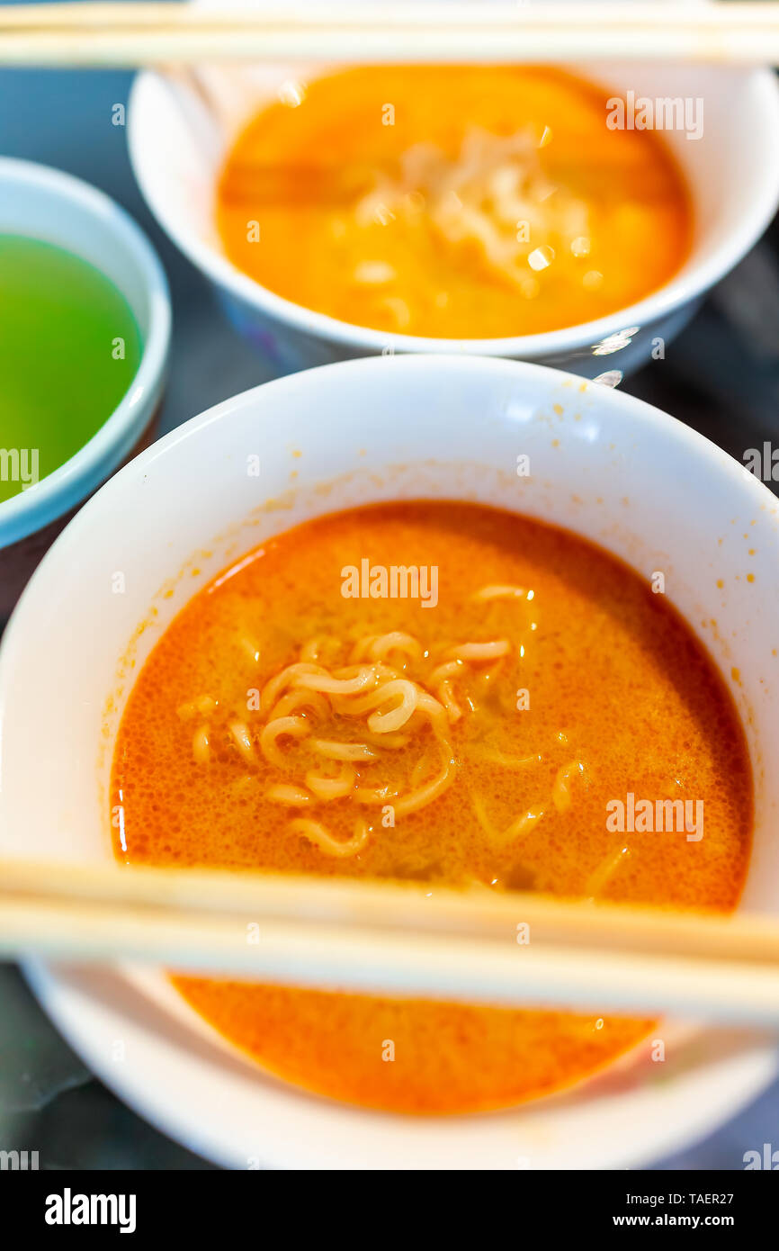 Macro closeup di Spicy Red ramen noodle soup bowl con bacchette giapponesi pasto asiatico e tè verde Foto Stock