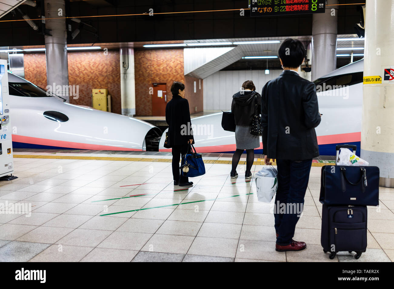 Tokyo, Giappone - Aprile 5, 2019: Stazione ferroviaria piattaforma in Ueno con shinkansen e salaryman persone con bagaglio in attesa in auto Foto Stock