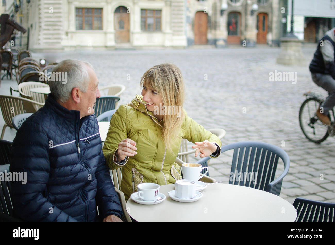Ritratto di felice coppia romantica con differenza di età di bere il caffè nella caffetteria con terrazza all'aperto nella città antica di mattina durante i primi anni di sp Foto Stock