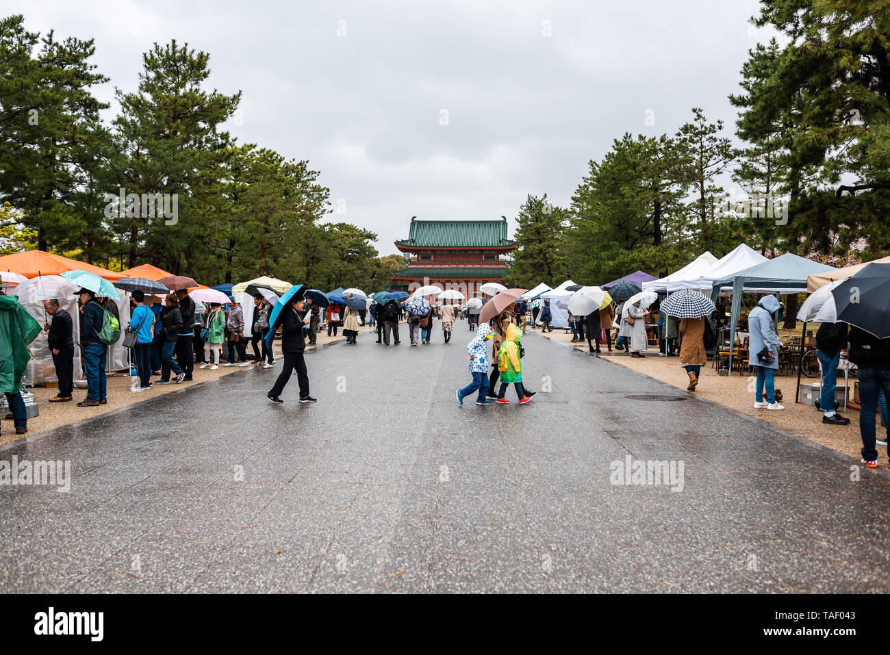 Kyoto, Giappone - 10 Aprile 2019: Persone con ombrelloni durante la giornata piovosa shopping nel mercato in Okazaki parco con vista del Santuario Heian Foto Stock