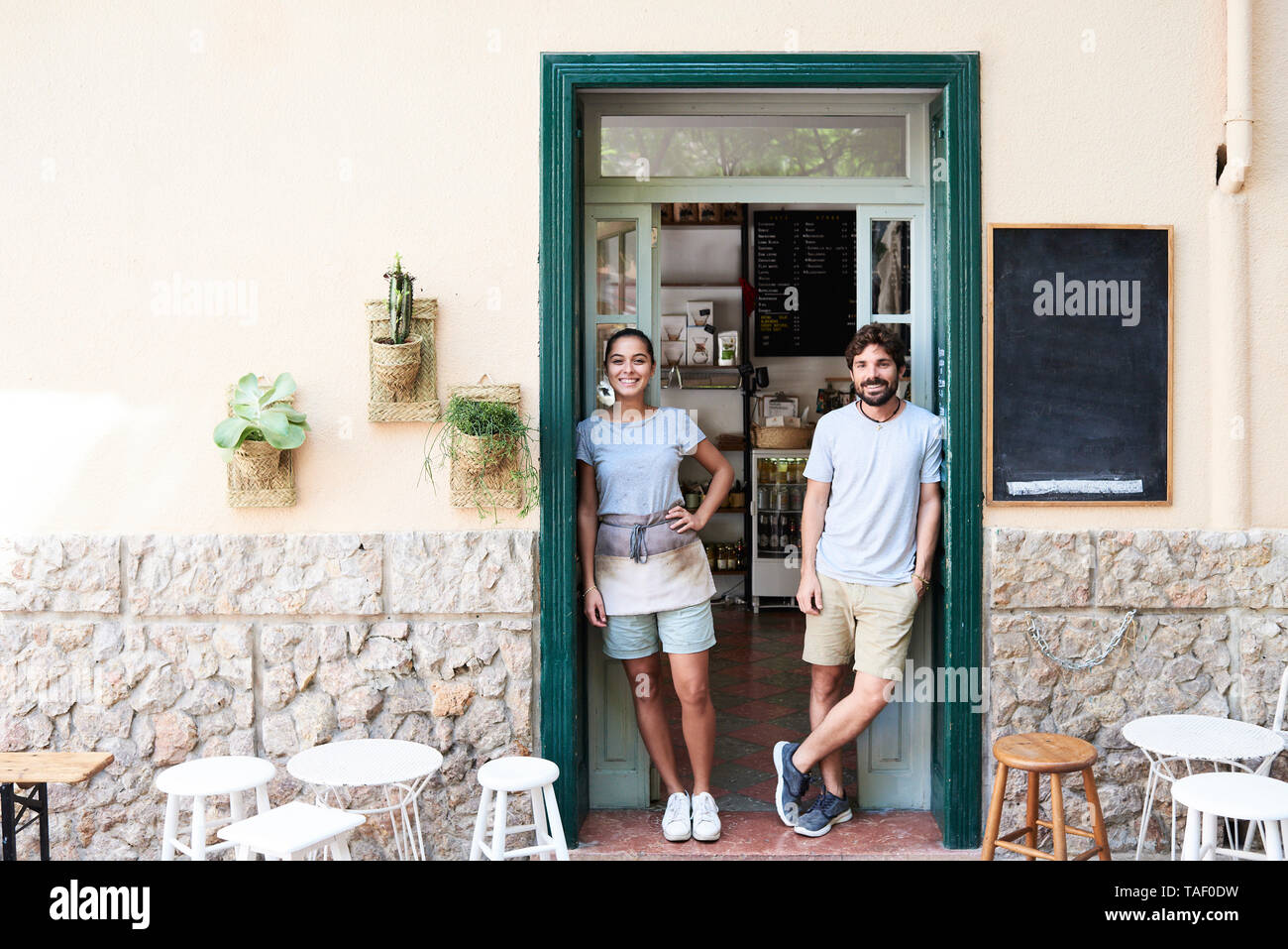 Ritratto di uomo sorridente e la donna in piedi alla porta di ingresso di un cafe Foto Stock
