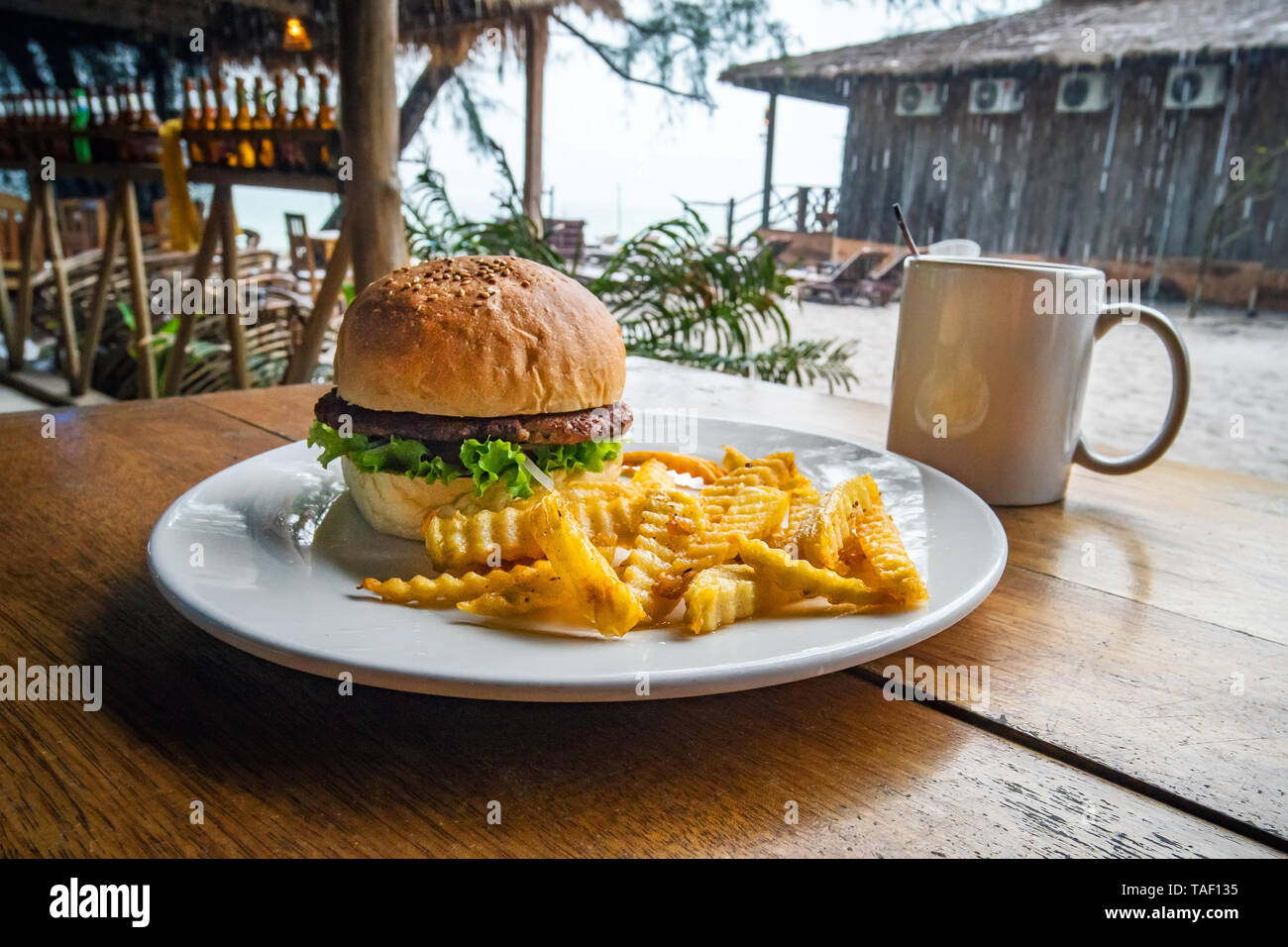 Freschi e saporiti hamburger e patatine fritte su un tavolo di legno. alimenti nocivi, nocivi per la salute. Prima colazione in street cafe. Foto Stock