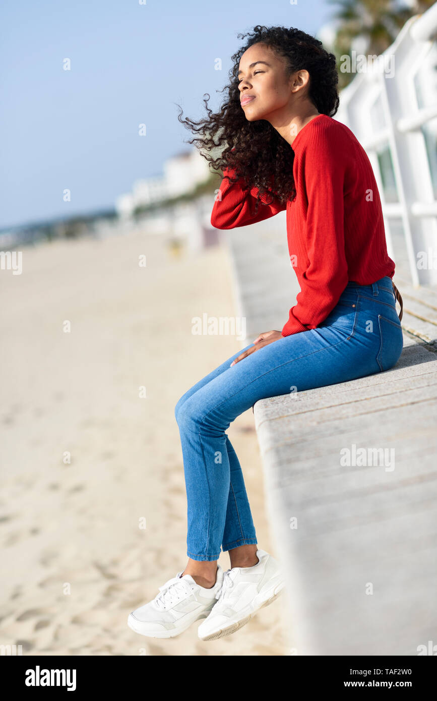 Giovane donna seduta sul lungomare Foto Stock